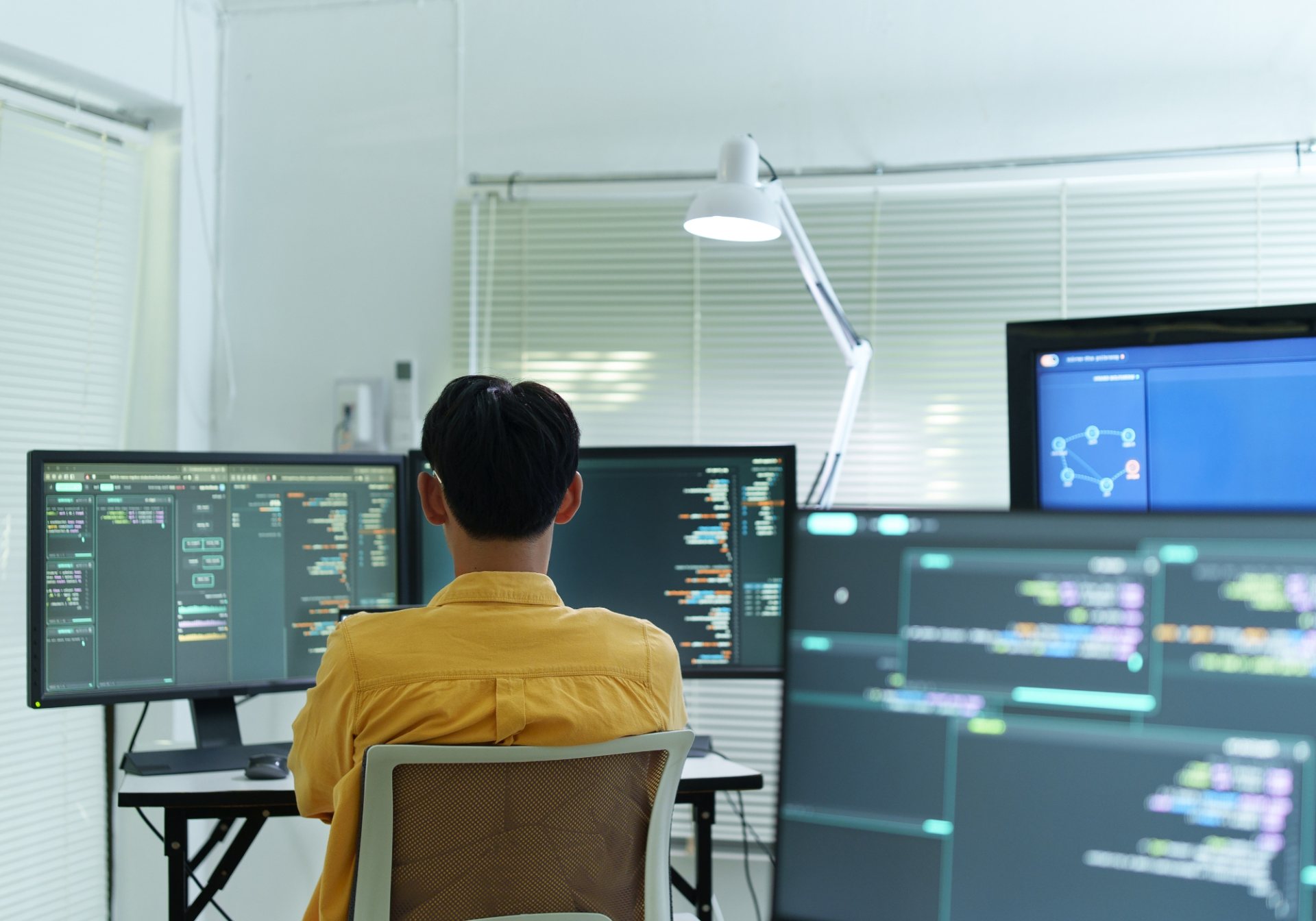 Developer at a multi-monitor workstation with code and a node graph, building a reinforcement learning environment
