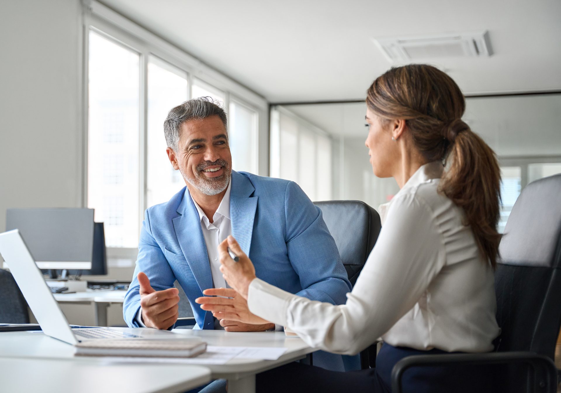 Account manager talking a customer through a renewal at a laptop in a bright office
