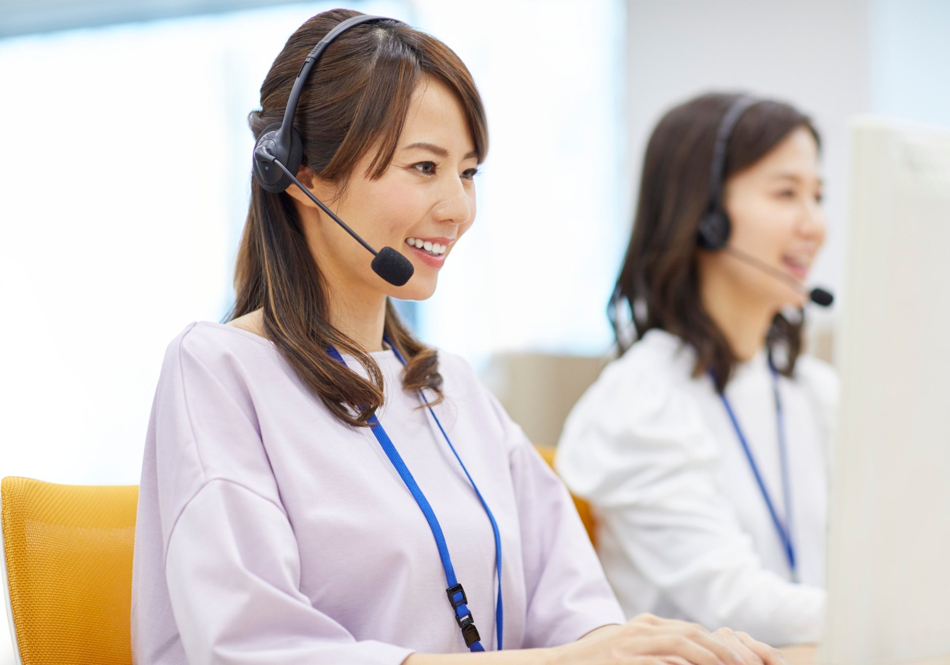 Smiling care agent with a headset at her workstation, offering a size exchange instead of a refund