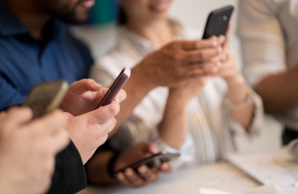 Group of shoppers browsing and messaging on their smartphones, representing social commerce support outsourcing to the Philippines