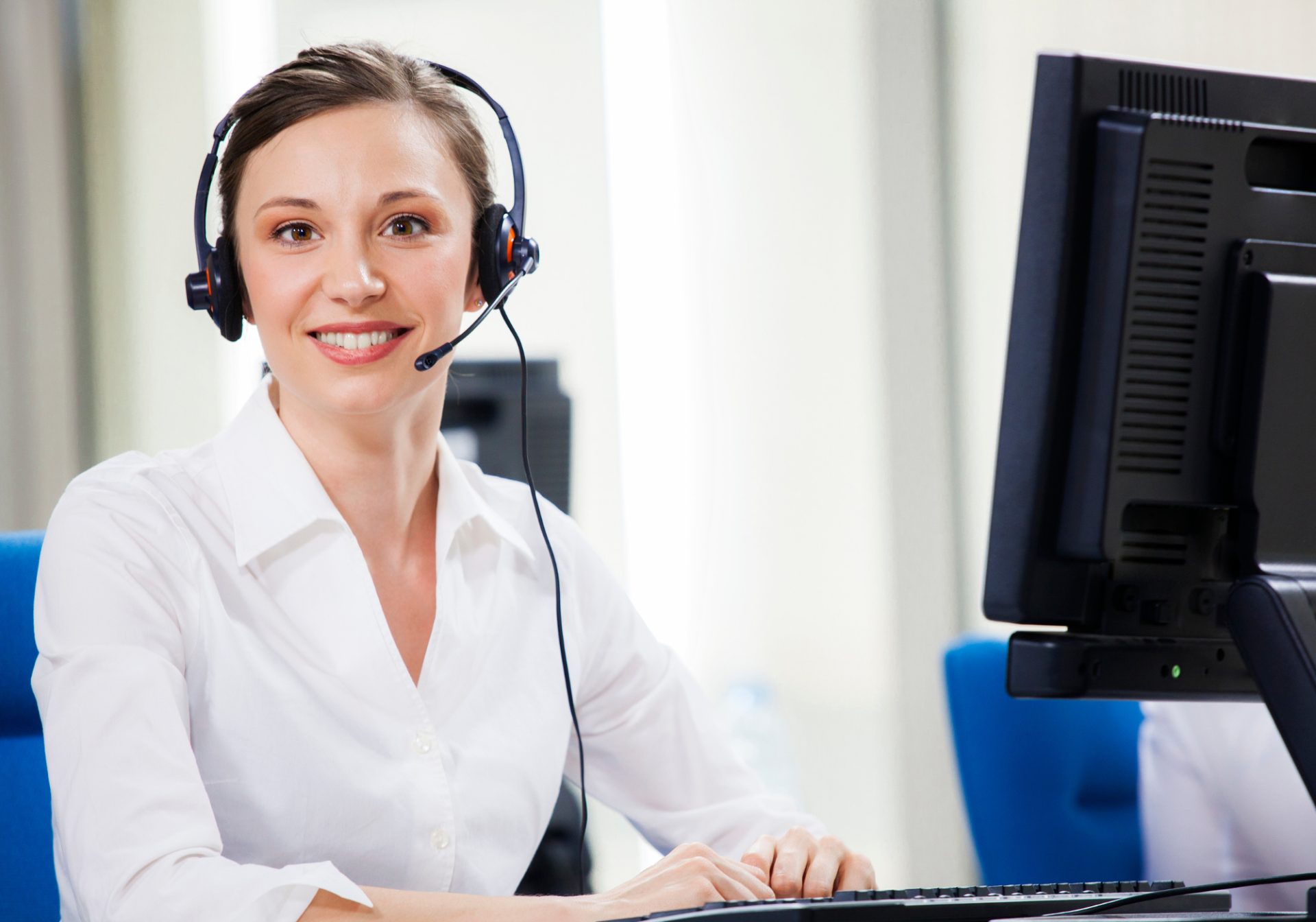 Smiling technology support agent with a headset at her workstation, ready to help a user with an account question