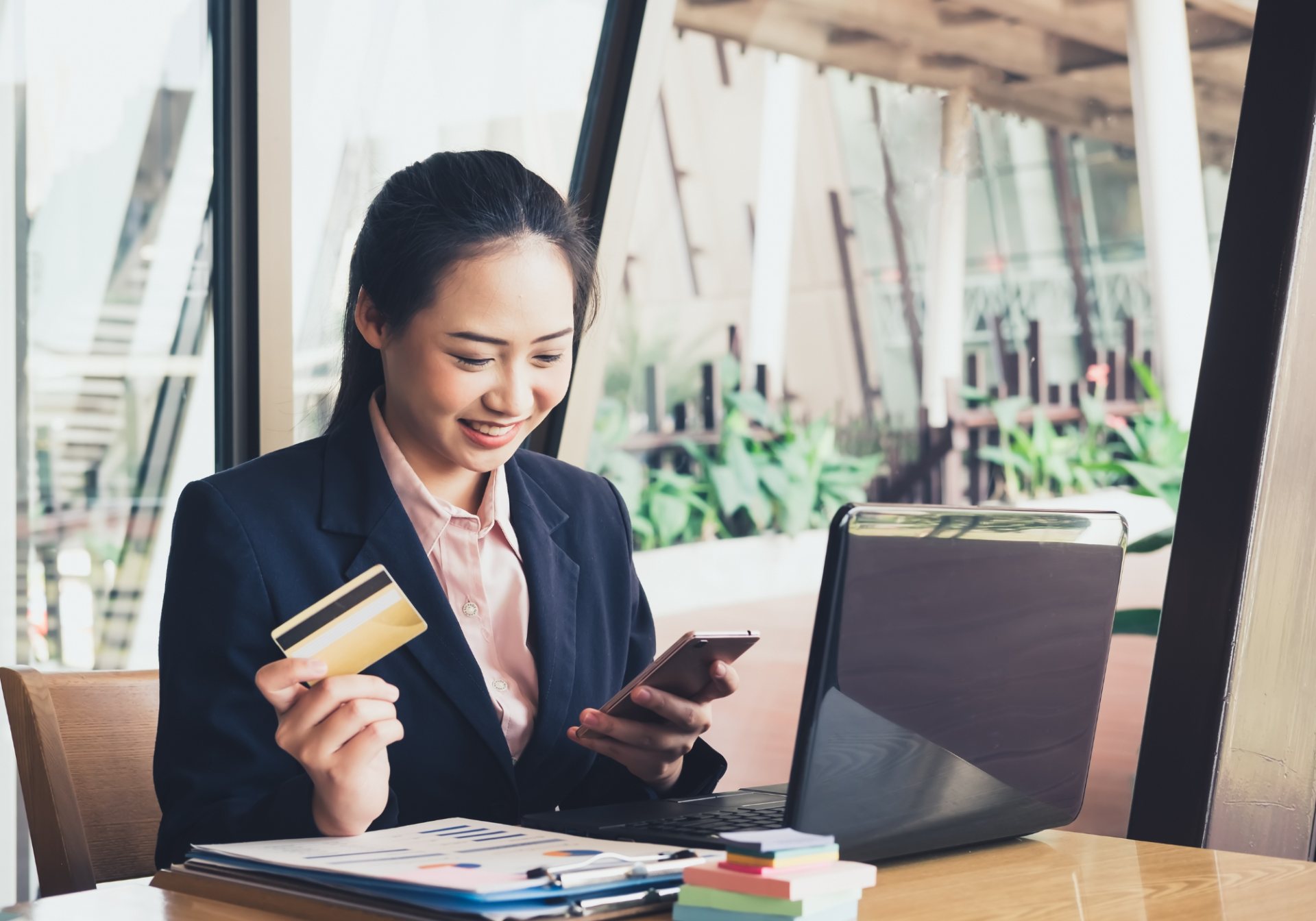 Smiling shopper holding a payment card and phone, checking out from a TikTok Shop order