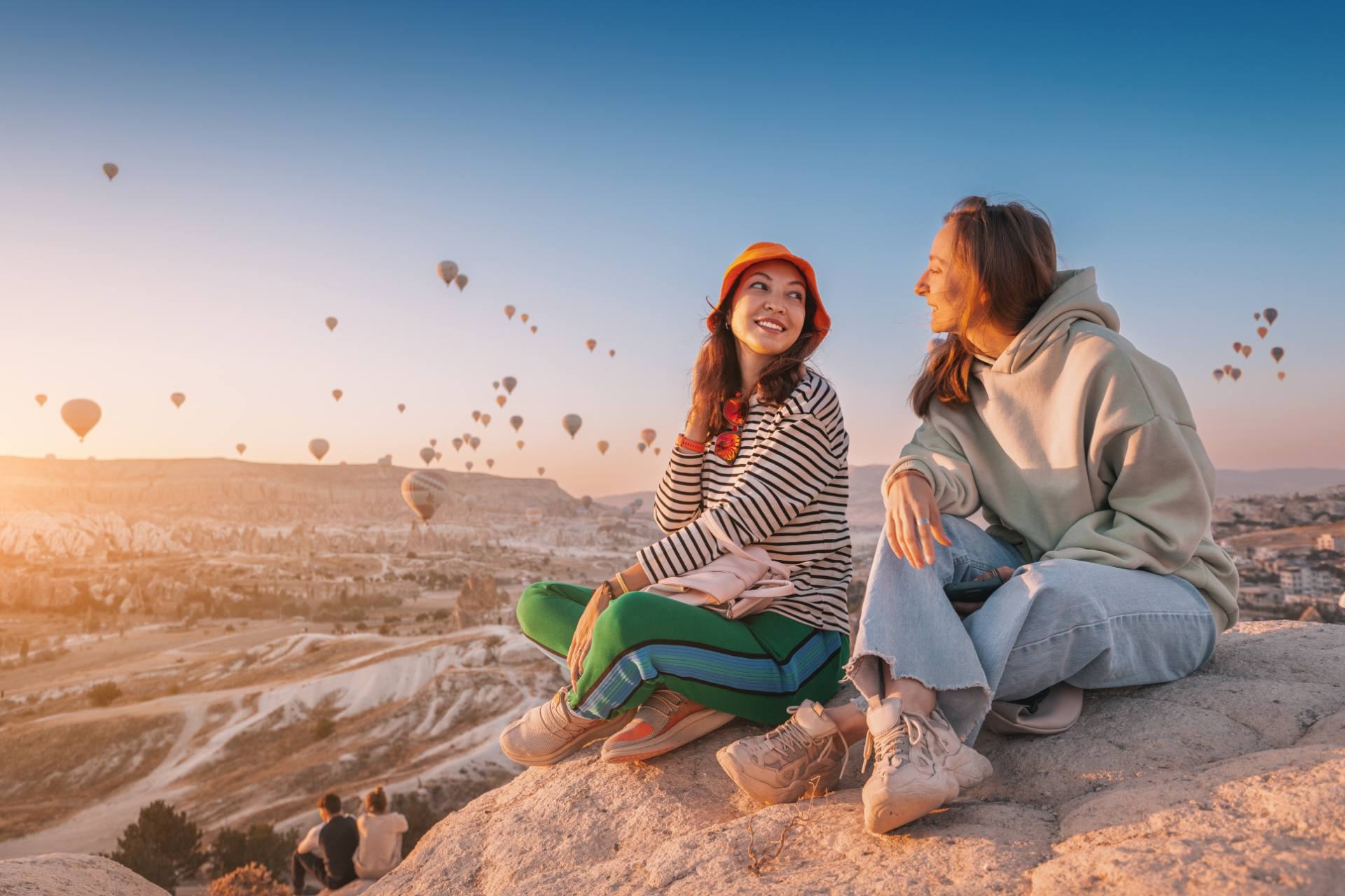 Two travelers watching hot air balloons at sunrise in Cappadocia, representing travel customer support delivered by Philippine BPO teams