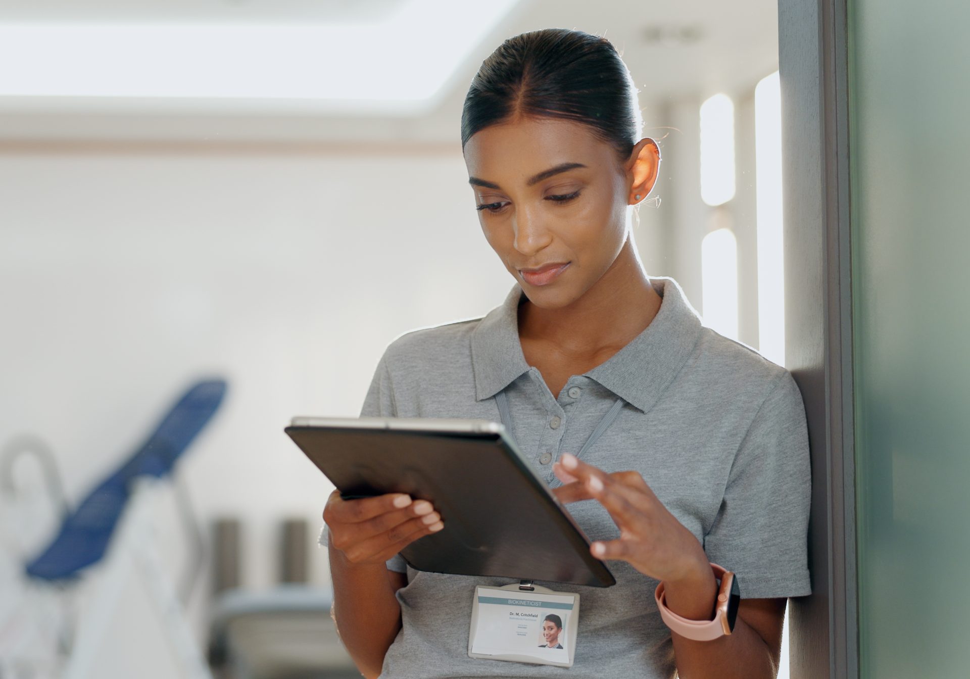 Rehabilitation clinician checking a treatment plan on a tablet in a physio clinic, care that workers' comp billing covers